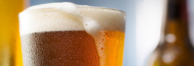 Beers Close-up pint of beer with foam spilling over side of glass