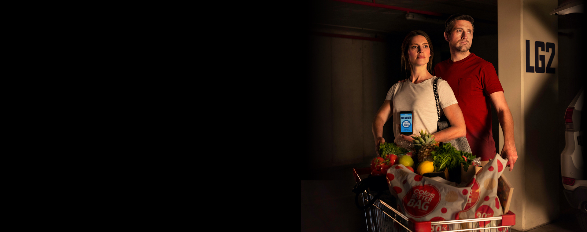 A couple with the flybuys app pushing their full trolley in a carpark