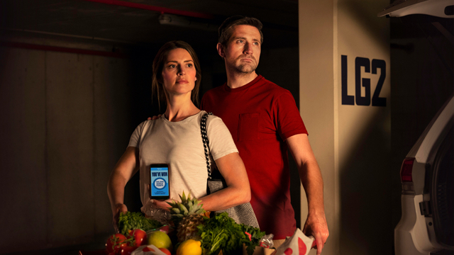 A couple with the flybuys app pushing their full trolley in a carpark