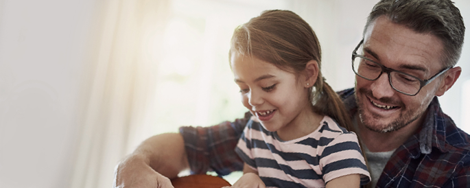 Dad with his daughter on his lap teaching her the guitar