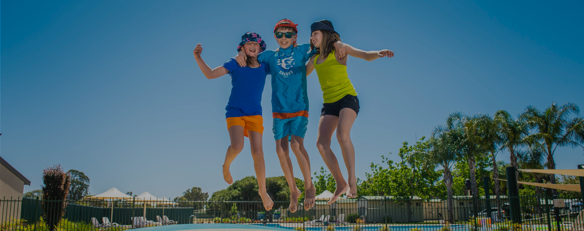 3 kids jumping on a bouncing pillow at a holiday park