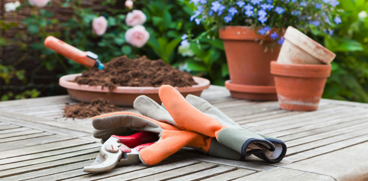 Gardening gloves laying on a garden table with plants in the background