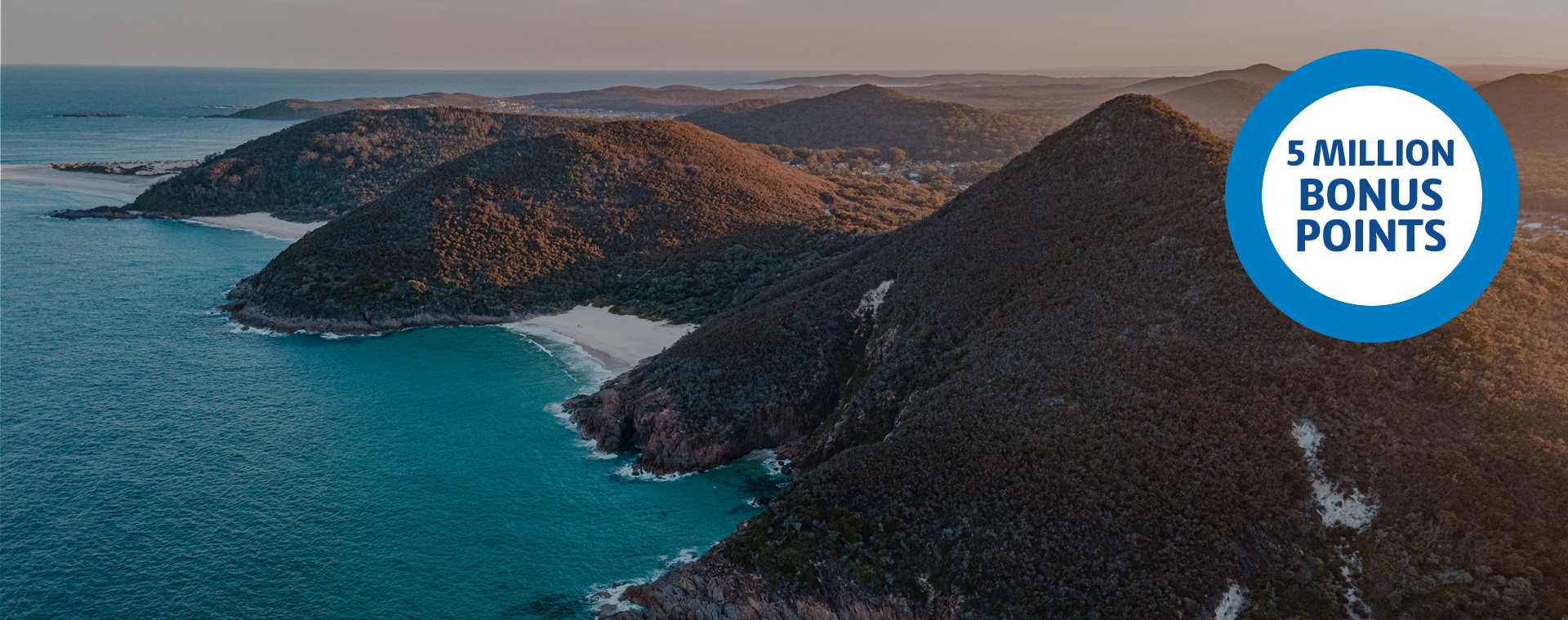 5 Million Bonus Points ring over an image of an aerial shot of a hilly beach