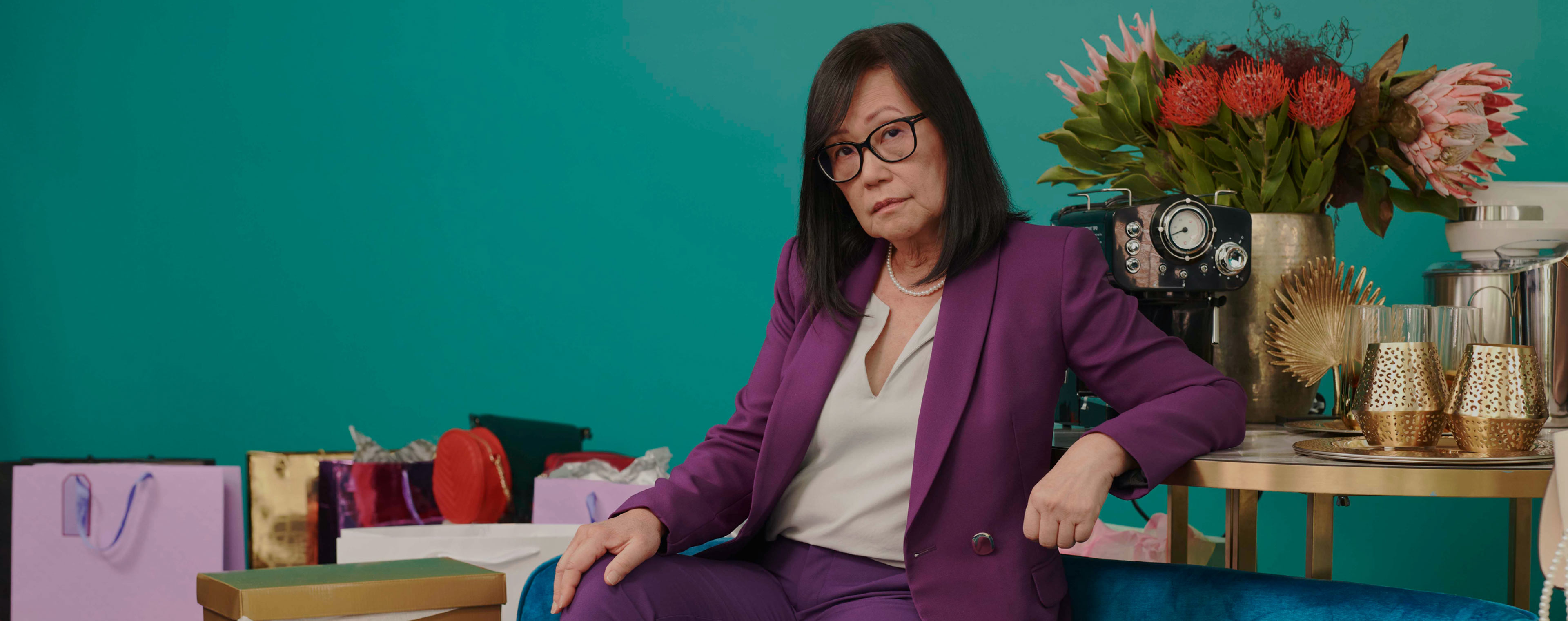 Lady in a purple suit sitting among a number of reward products
