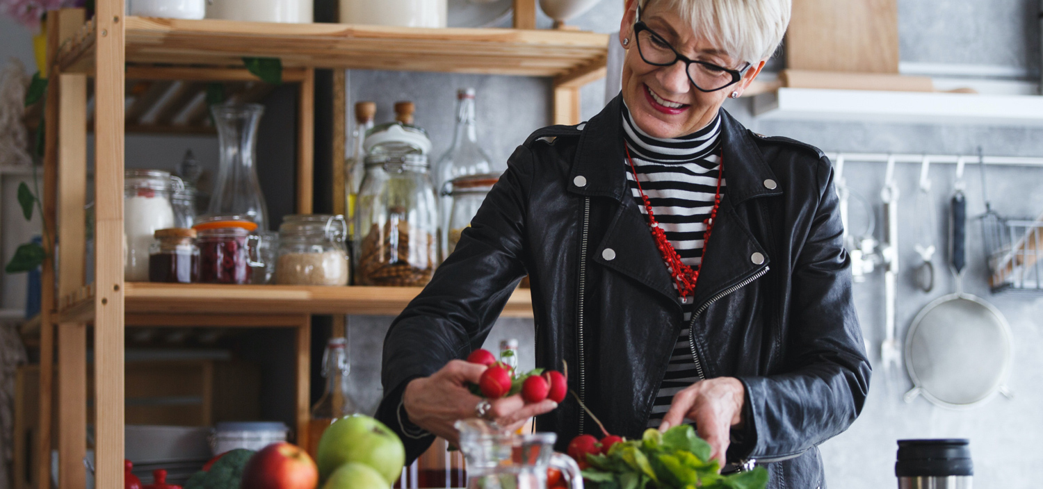 Lady in a kitchen looking at food on the bench