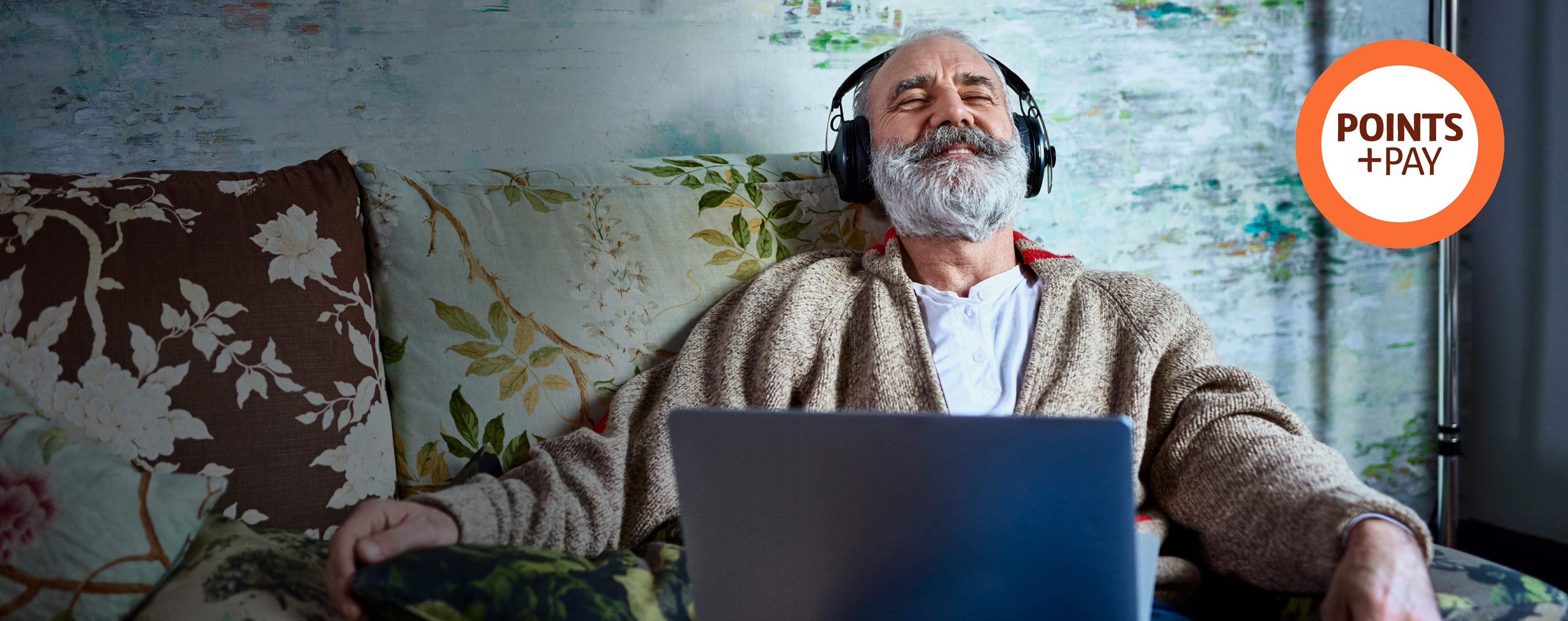 Man sitting on a couch listening to music via his headphones