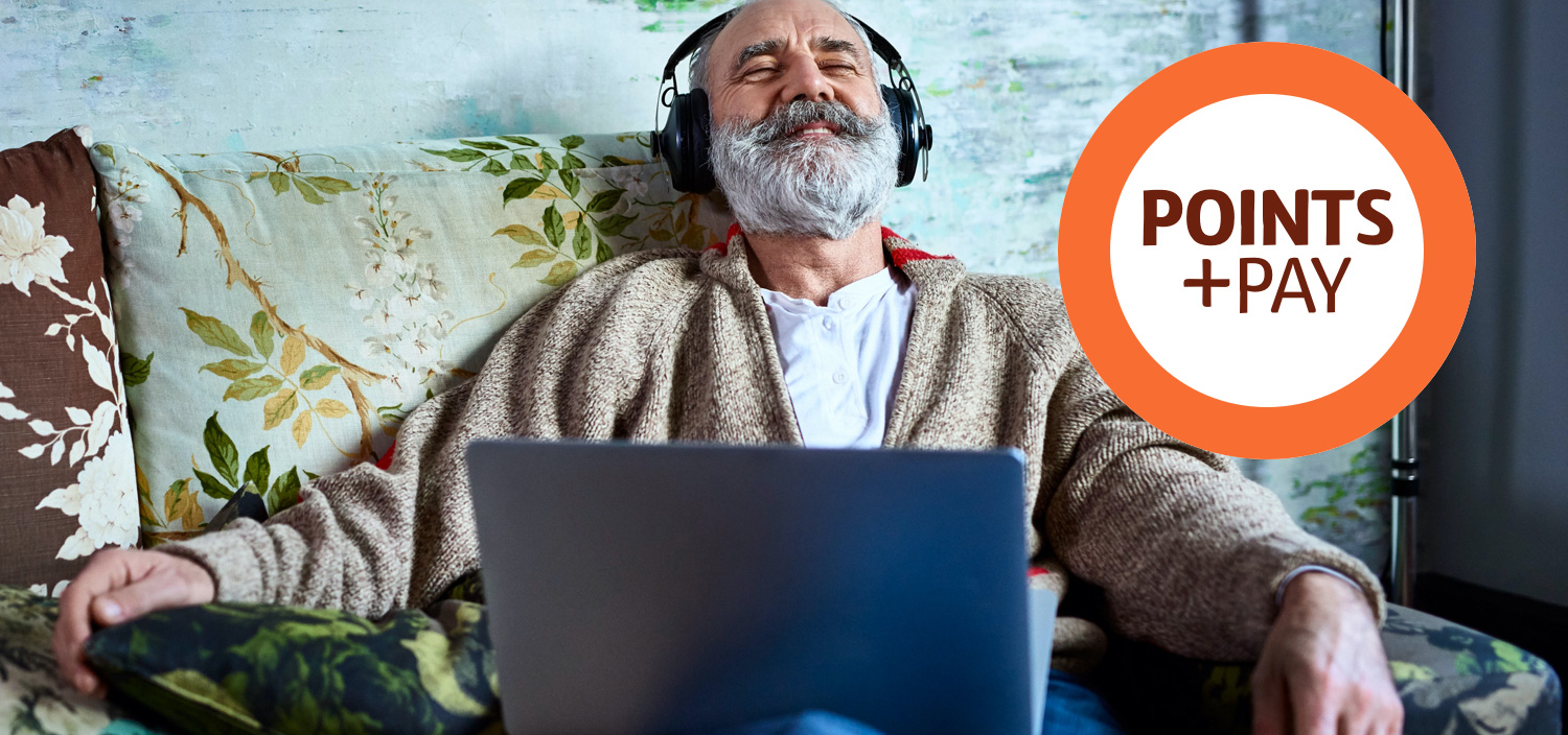 Man sitting on a couch listening to music via his headphones