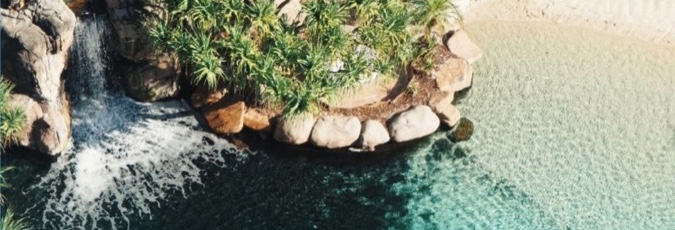 Take a Vacay and collect 1 point per $1 spent! Image of a beautiful tropical lagoon with a waterfall