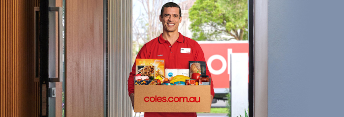 Enjoy unlimited delivery and double Flybuys points with Coles Plus Coles delivery driver in red, delivering a box of Coles groceries