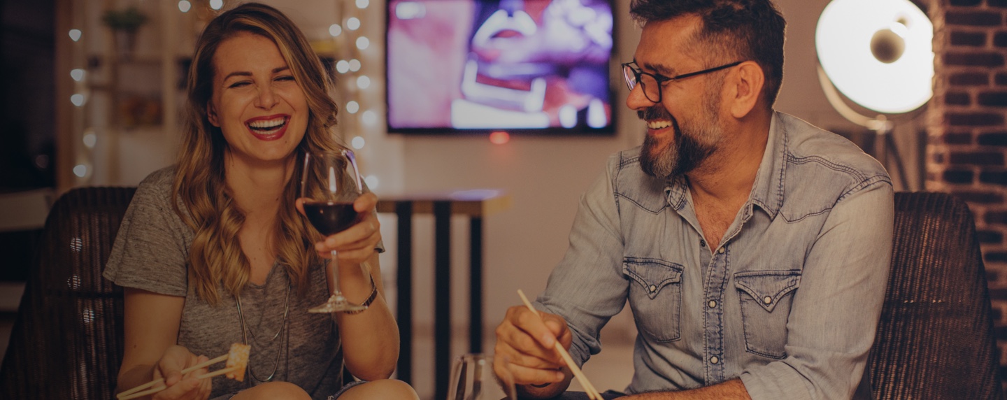 Smiling European couple drinking wine and eating sushi