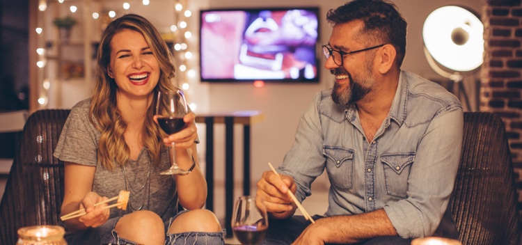 Smiling European couple drinking wine and eating sushi