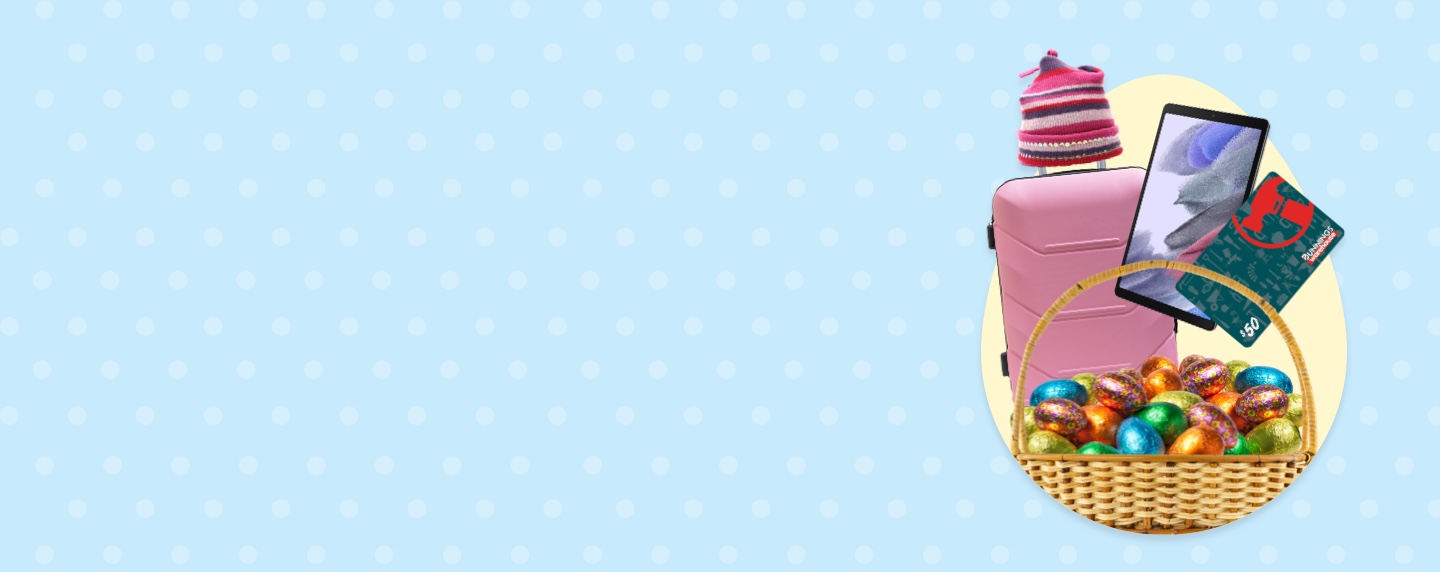Blue spotted background with woven basket filled with colourful foil Easter eggs, $50 Bunnings Warehouse gift card, iPad and pink beanie atop of pink suitcase