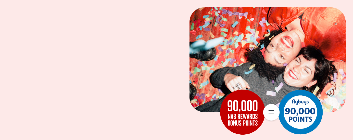 Two ladies laying on the floor being showered in confetti next to a 90,000 NAB points ring and 90,000 Flybuys points ring 