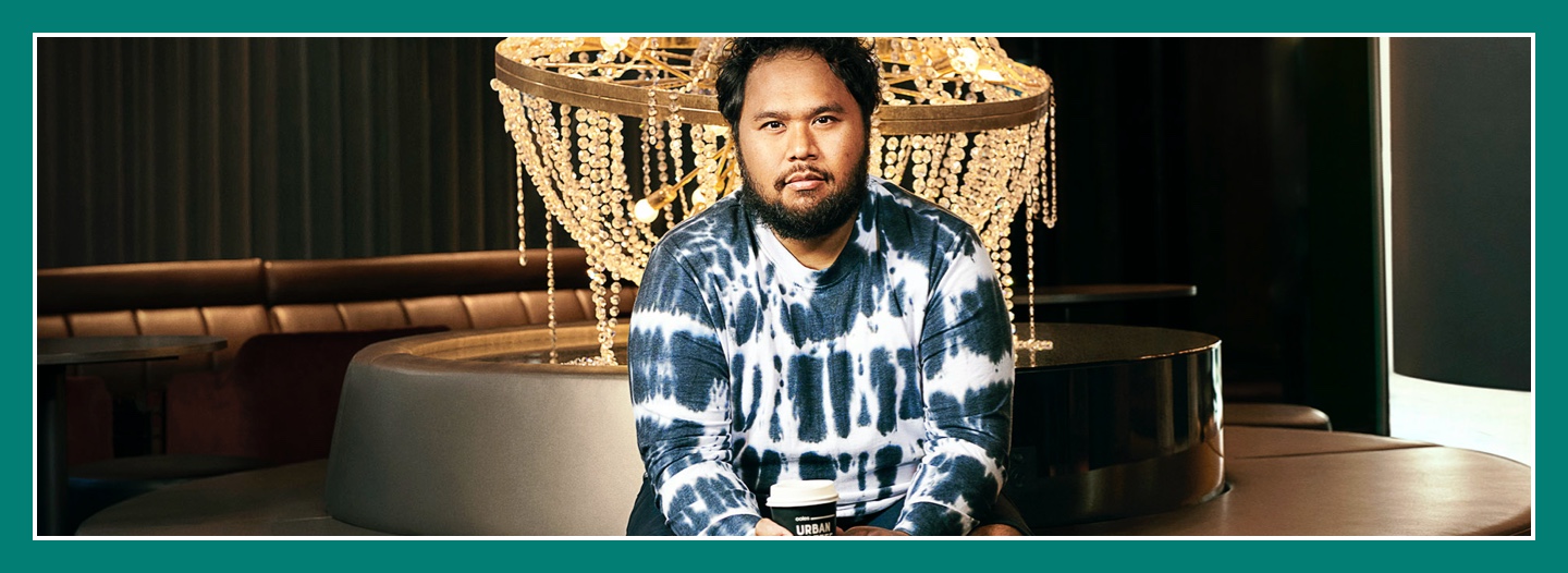 Flybuys' top 10 member Moris sitting down to chandelier with Coffee cup