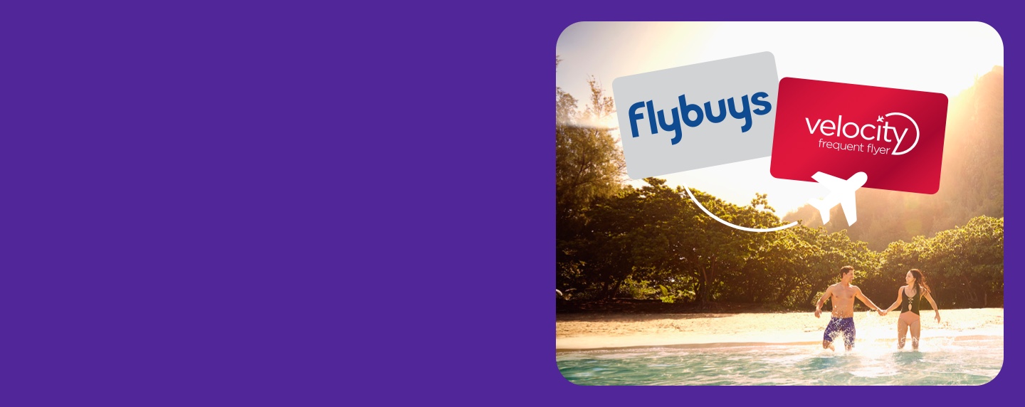 Couple holding hands knee deep in water with a Flybuys and Velocity Frequent Flyer card above their heads