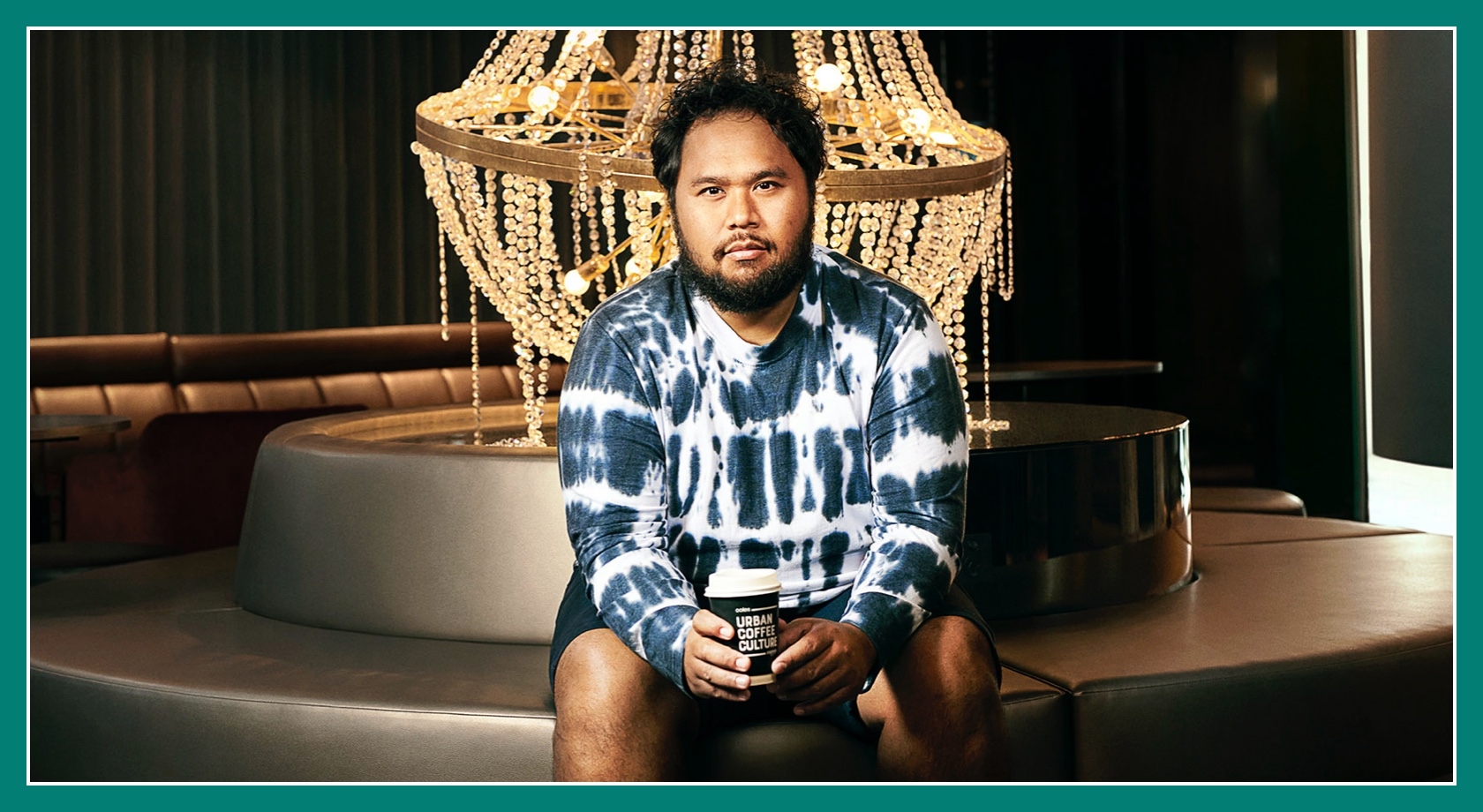 Flybuys' top 10 member Moris sitting down to chandelier with Coffee cup