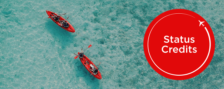 Two red canoes out in ocean by status credits roundel