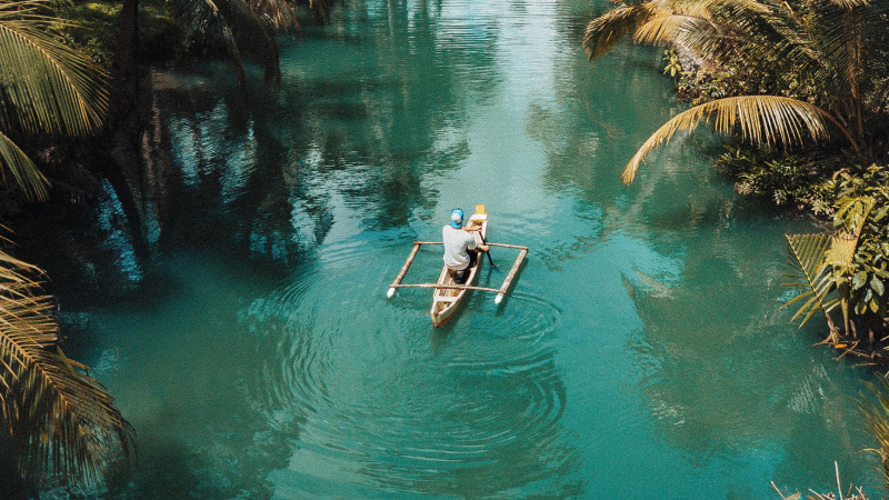 Birdeye view of man gliding down down the river in a canoe