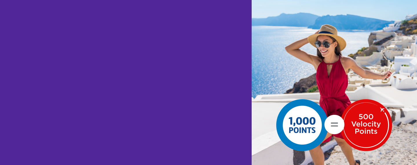 Women in a red dress holding her hat on the coast of Santorini.