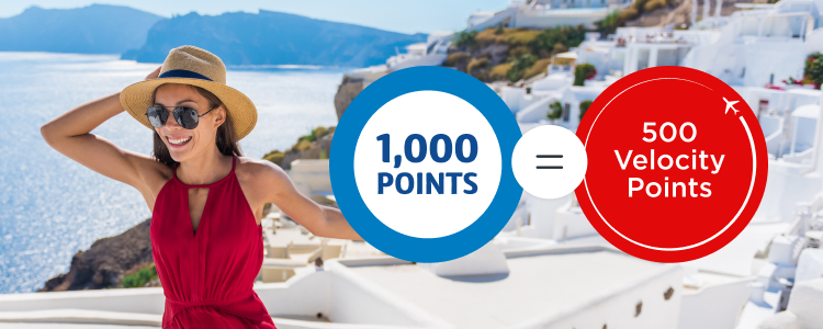Women in a red dress holding her hat on the coast of Santorini.