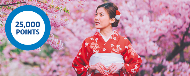 Japanese girl in her red kimono standing next to Cherry Blossom trees in Japan
