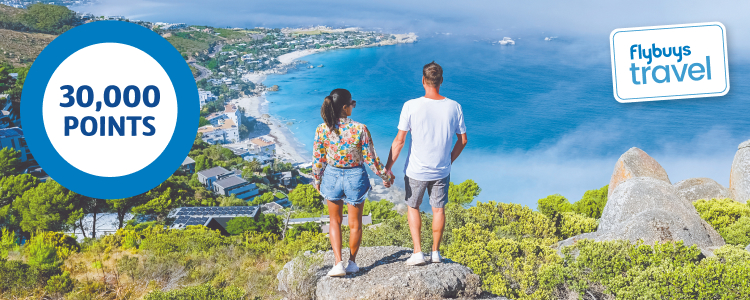 Couple holding hands on cliff top overlooking seaside town