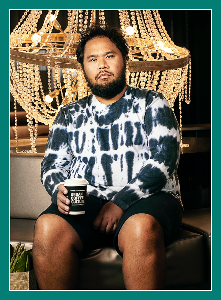 Flybuys' top 10 member Moris sitting next to a chandelier holding a coffee cup